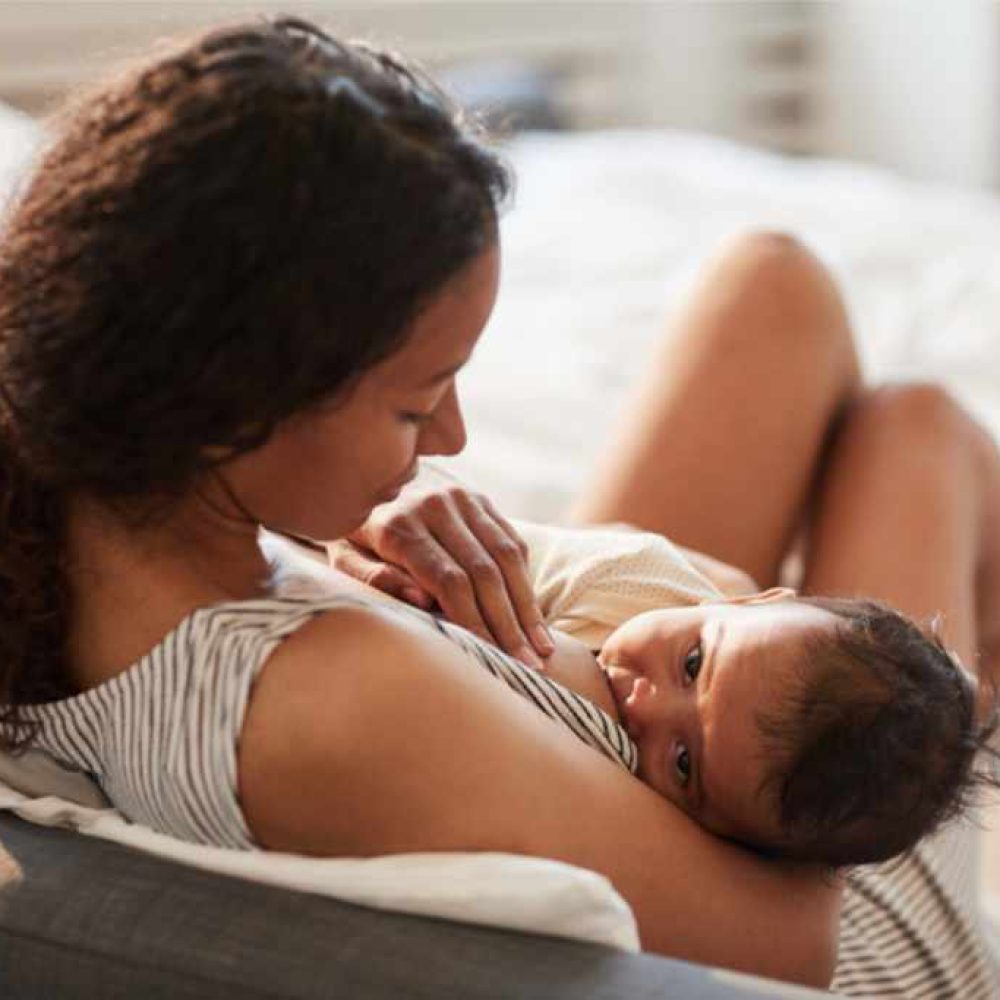Young Mother Breastfeeding Baby at Home after lactation consultation